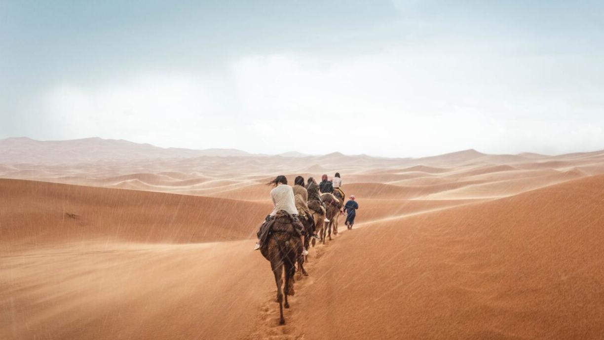 Karavaani kulkee Saharassa vesisateessa.