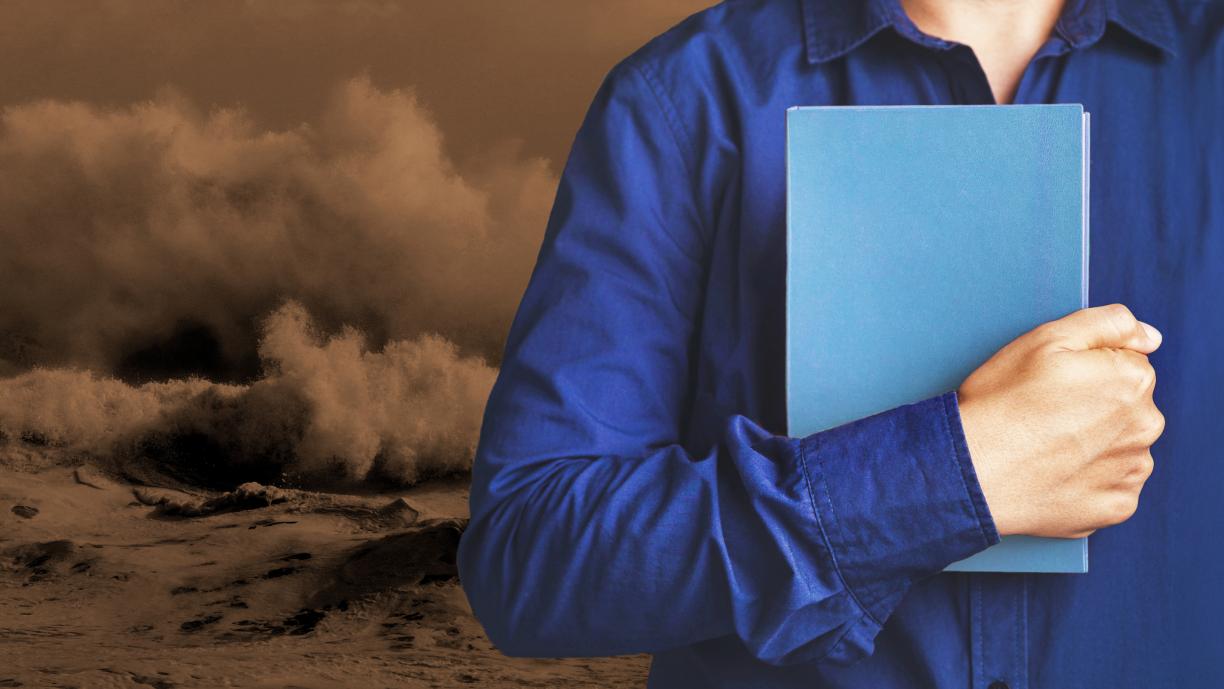 Kuvituksenomainen kuva, jossa siniseen paitaan pukeutunut henkilö pitää kirjaa kädessään rintansa edessä. Taustalla näkyy punaisenruskeaa, myrskyävää merta.