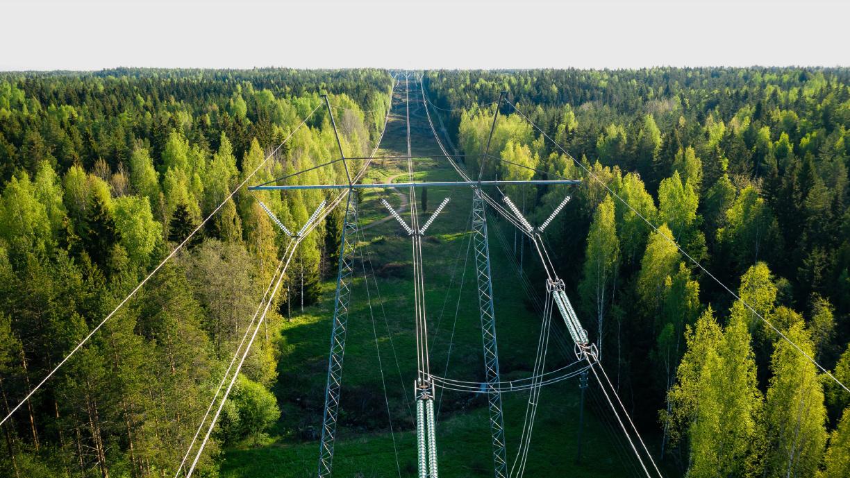 Suuri voimalinja halkoo metsäistä maisemaa.