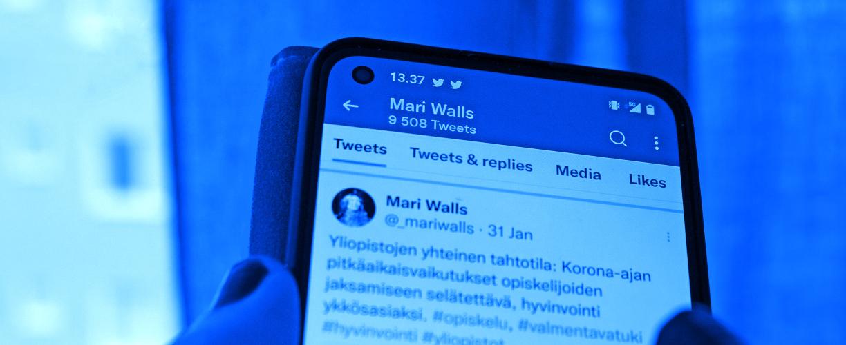 Sinisävyinen valokuva älypuhelimen ruudusta, jolla on näkyvissä Mari Wallsin Twitter-tili. Tilin tiedoissa lukee, että tilillä on 9508 twiittiä.