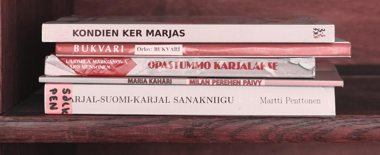 Viisi karjalankielistä kirjaa kirjahyllyssä.