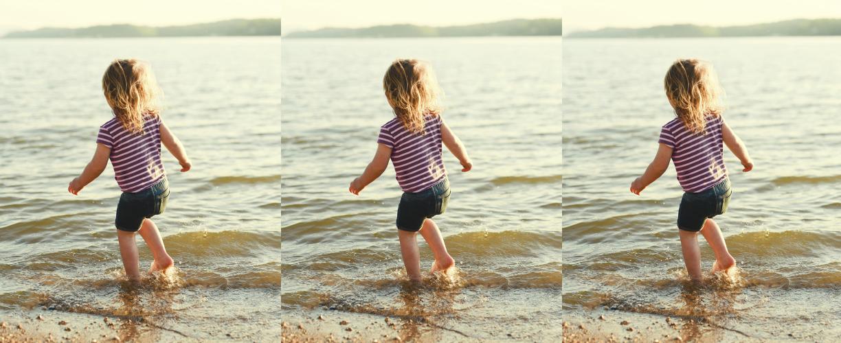 Lapsi juoksemassa matalassa rantavedessä.