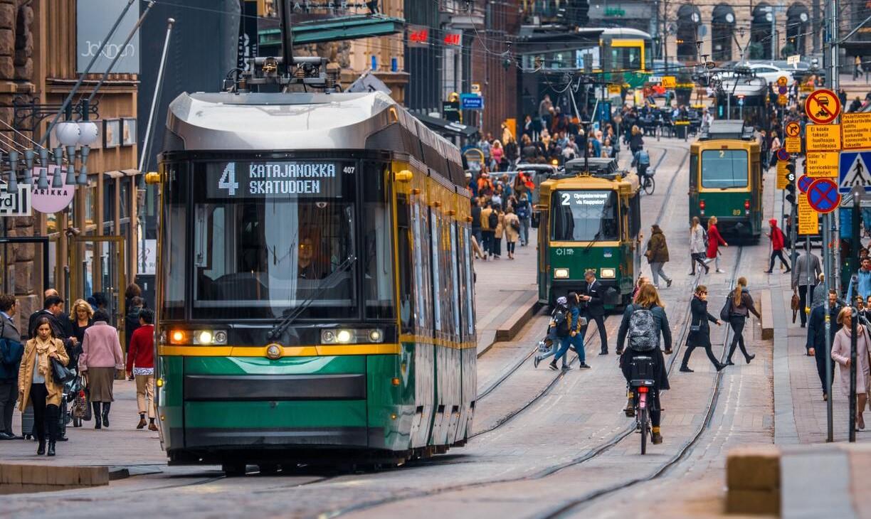 Helsingin Aleksanterinkadulla kulkee raitiovaunuja, pyöräilijöitä ja kävelijöitä.