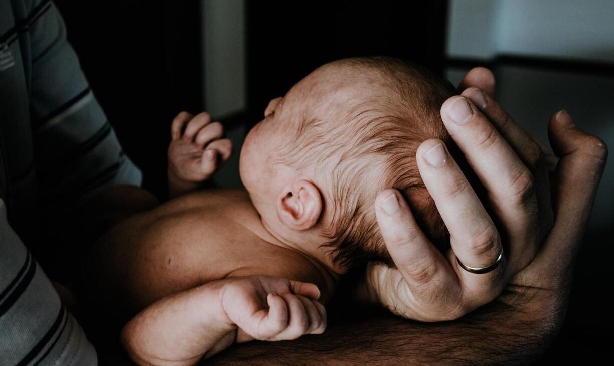 Aikuinen pietelee pientä vauvaa käsissään.