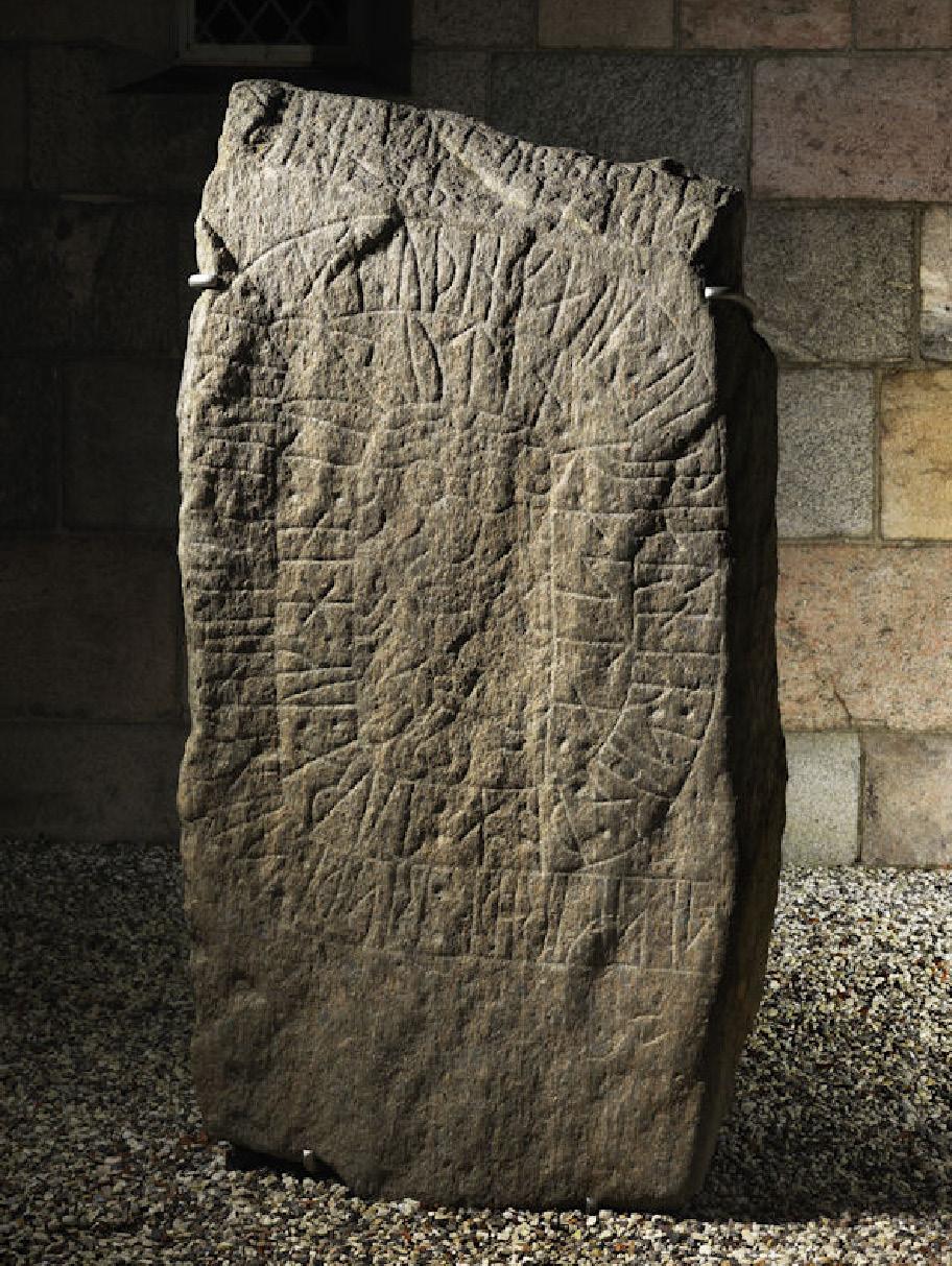 Suuri suorakulmion malliseksi muotoiltu kivi, jonka laakean sivun pintaan on hakattu koristellista kirjoitusta. 