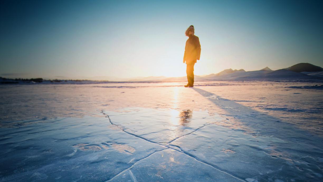 Ihminen kävelee jäällä, jossa on murtumia.