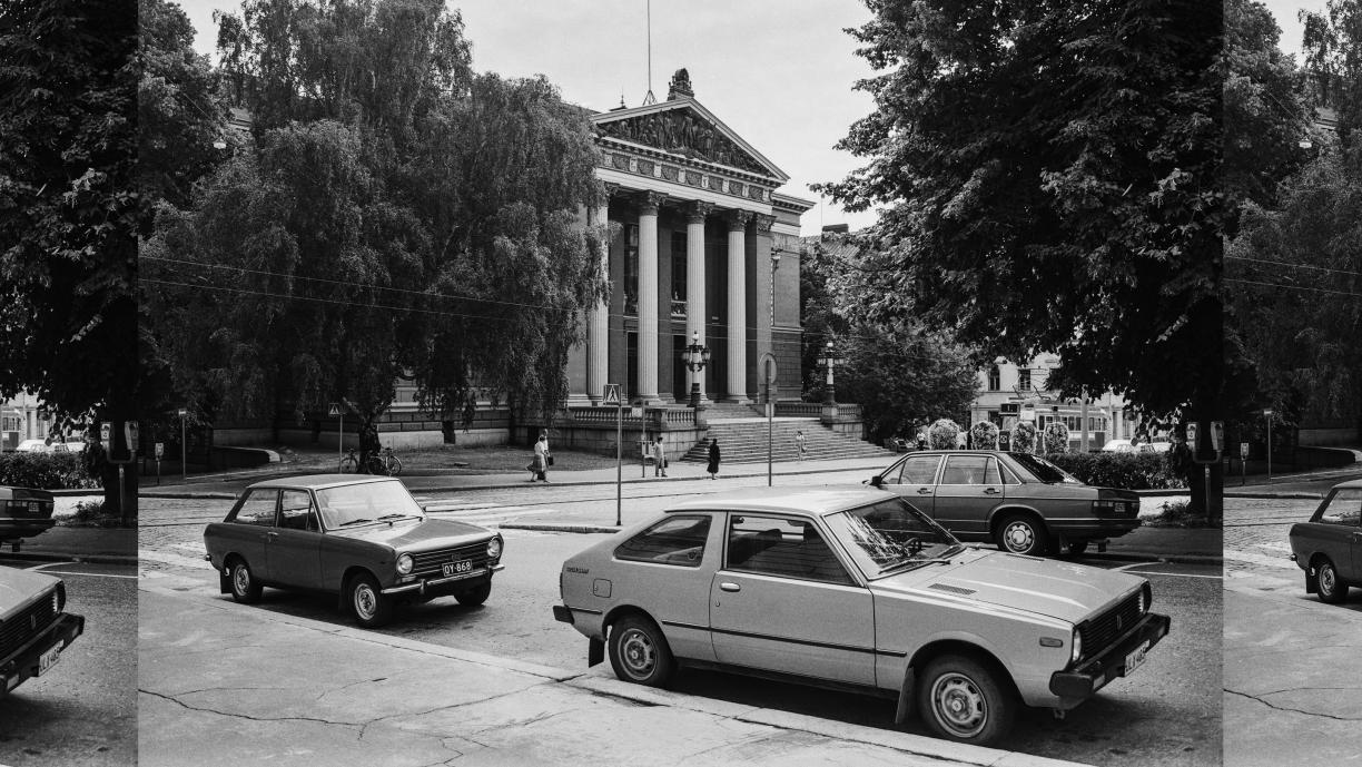 Mustavalkoinen valokuva, jonka keskellä näkyy Säätytalon pylväin koristeltu julkisivu. Ympärillä on tuuheita lehtipuita ja kadulla muutamia jalankulkijoita sekä kolme 1970- tai 1980-luvun autoa.
