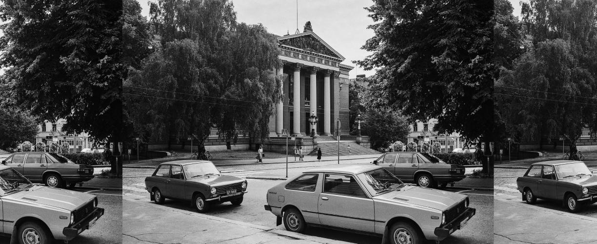 Mustavalkoinen valokuva, jonka keskellä näkyy Säätytalon pylväin koristeltu julkisivu. Ympärillä on tuuheita lehtipuita ja kadulla muutamia jalankulkijoita sekä kolme 1970- tai 1980-luvun autoa.