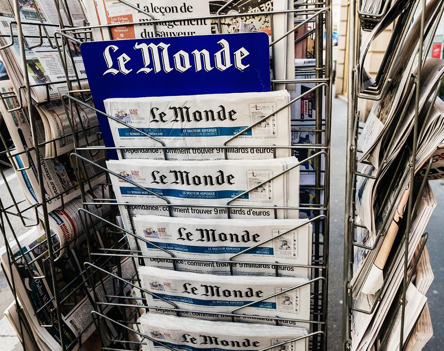 Metallinen sanomalehtiteline täynnä sanomalehtiä. Etummaisena näkyy Le Monde -lehden sininen kyltti ja pitkä rivi päivän Le Monde -lehtiä.