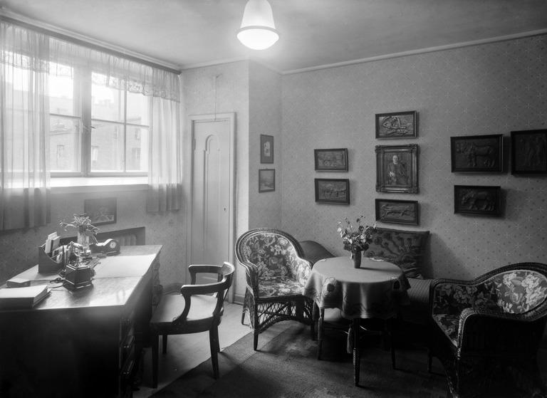 Mustavalkoinen valokuva vuodelta 1926, jossa on rehtorin huone. Huoneessa on työpytä ja pieni istuinryhmä.