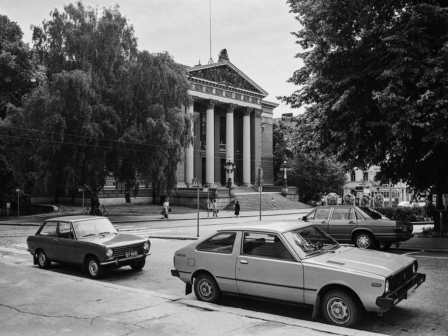 Mustavalkoinen valokuva, jonka keskellä näkyy Säätytalon pylväin koristeltu julkisivu. Ympärillä on tuuheita lehtipuita ja kadulla muutamia jalankulkijoita sekä kolme 1970- tai 1980-luvun autoa.