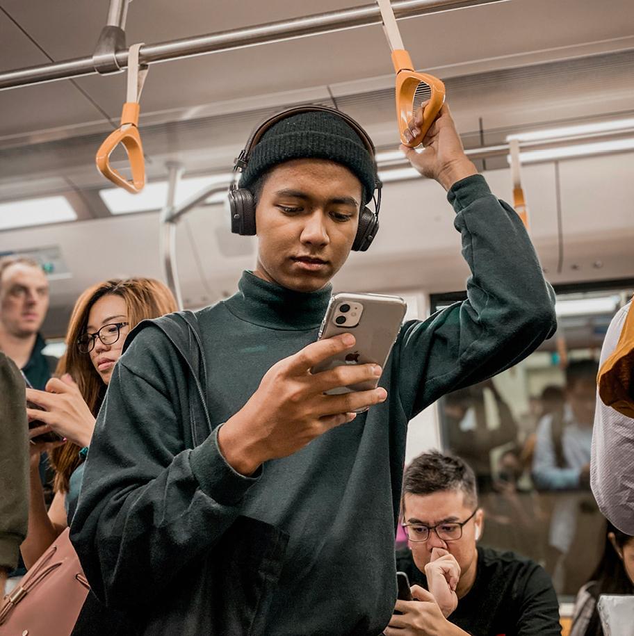 Useita henkilöitä matkustaa metrossa. Suurin osa heistä katsoo puhelintaan.