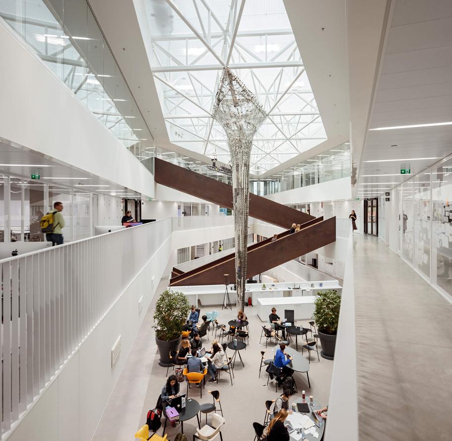 Sisäkuva suuresta modernista rakennuksesta. Avoin hallimainen käytävätila, jonka keskellä on pyötäryhmiä.